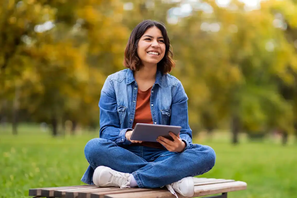 A woman using her tablet on a park bench